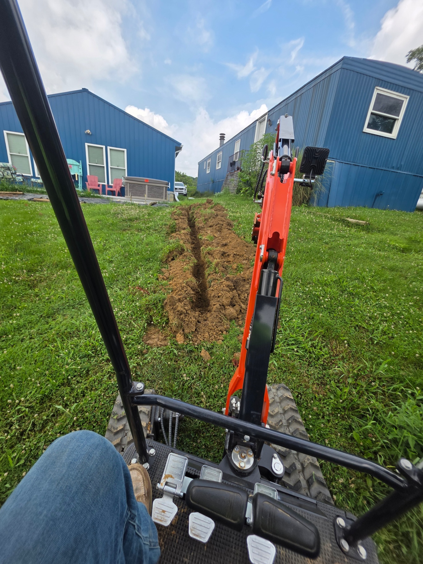 Mini excavator trenching a drainage line across a Northern Kentucky yard