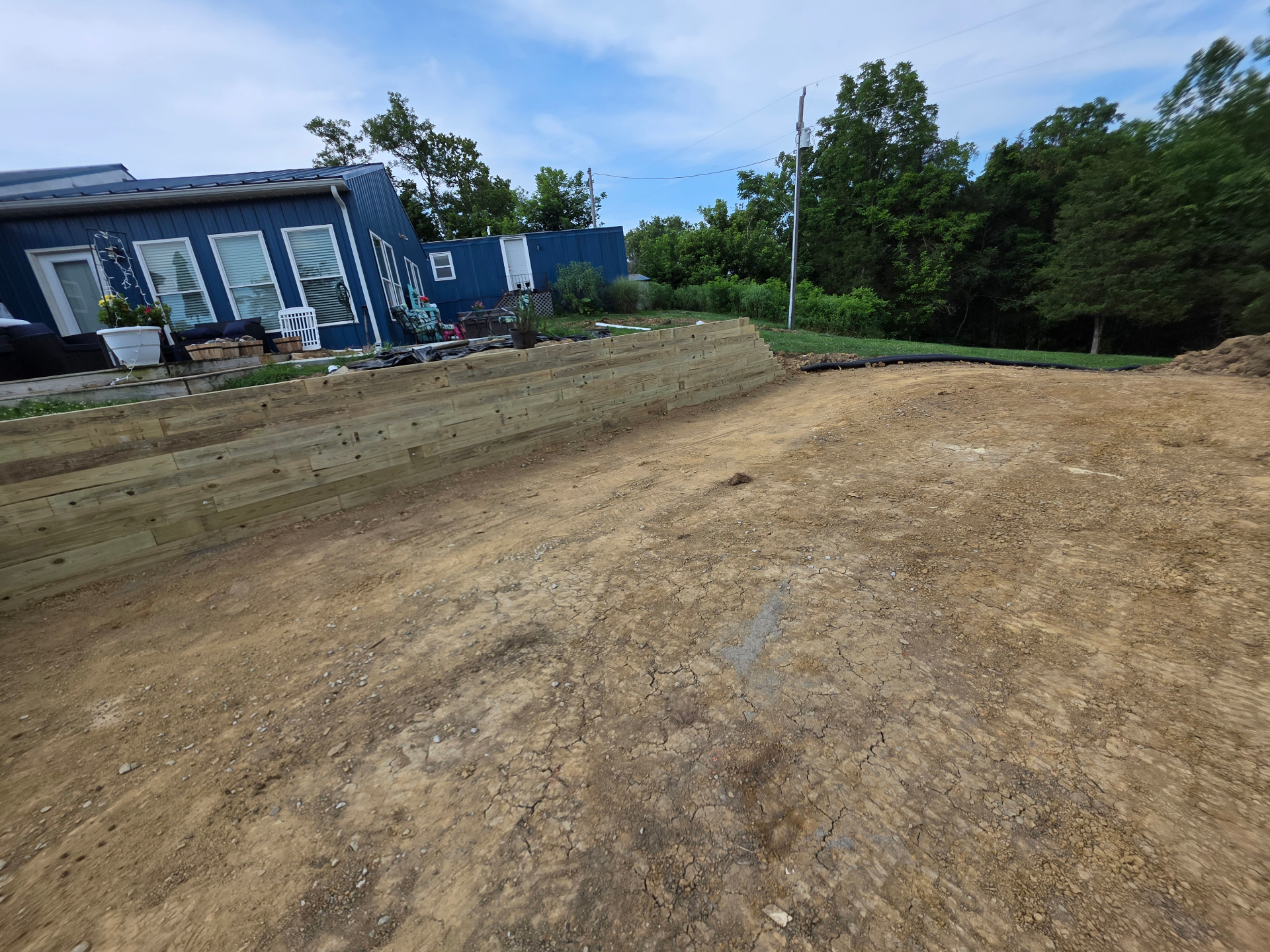 Side view of stacked pressure-treated timber retaining wall along a home in Northern Kentucky
